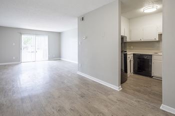 an empty living room and kitchen with white walls and wood flooring